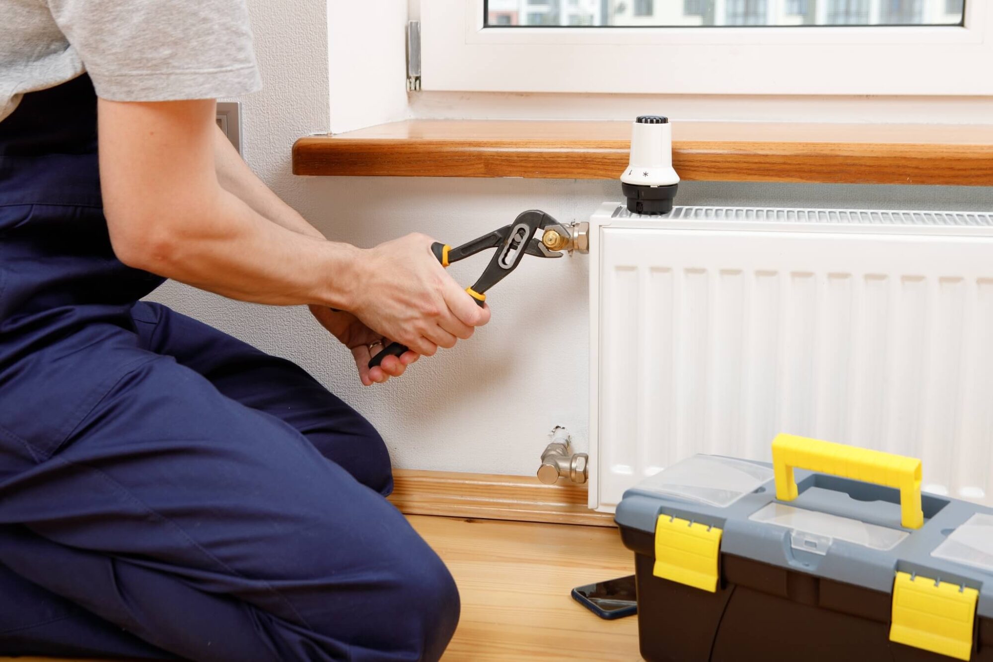 fachowiec zakłada instalacje wodną przy kaloryferze