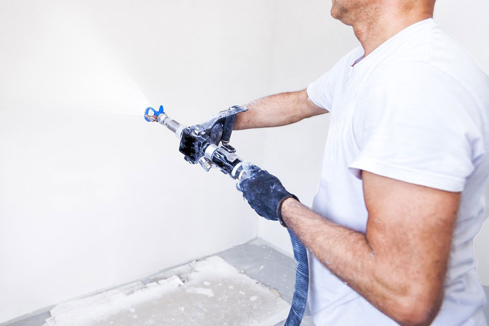 fachowiec nakłada szpachle z agregatu na ścianę